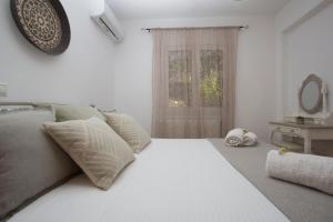 un letto bianco con cuscini e una finestra in una stanza di Quercus Villa, Achilleion Palace, Corfu a Perama