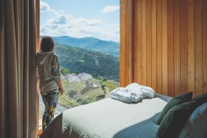 una mujer mirando por una ventana a una vista de montaña en Casa do Arco by Douro Exclusive, en São Cristóvão do Douro