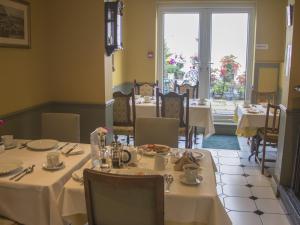 un restaurante con mesas y sillas blancas y una ventana en Albert & Victoria Guest House, en Eastbourne