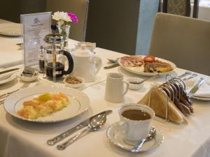 un tavolo con piatti e una tazza di caffè di Albert & Victoria Guest House a Eastbourne
