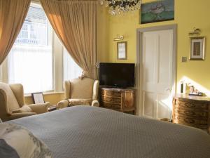 a bedroom with a bed and a tv and a window at Albert & Victoria Guest House in Eastbourne