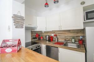 a kitchen with white cabinets and a sink at T2 (38m2) BOULOURIS -St RAPHAEL, 150 mètres de la mer in Saint-Raphaël