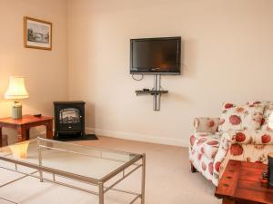 a living room with a couch and a tv on the wall at The Old Nursery in Much Wenlock