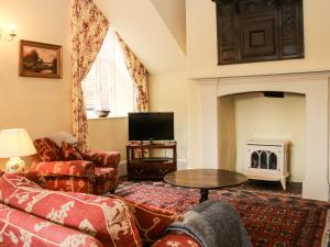 a living room with a couch and a fireplace at The Butlers Quarters in Much Wenlock