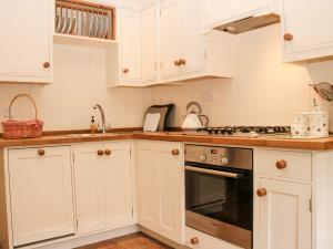 a kitchen with white cabinets and a stove top oven at The Butlers Quarters in Much Wenlock
