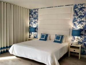 - une chambre avec un grand lit blanc aux accents bleus dans l'établissement Hotel Cristal Praia Resort & SPA, à Praia da Vieira