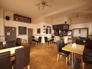 Hussar Inn في مارغايْت: غرفة طعام مع طاولات وكراسي ومطبخ