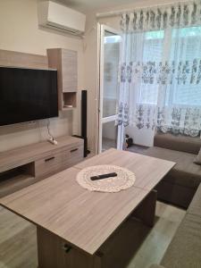 sala de estar con mesa y TV de pantalla plana en ЗАРА en Ruse