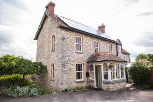 una antigua casa de piedra con un salón acristalado delante de ella en Withy Cottages en Langport