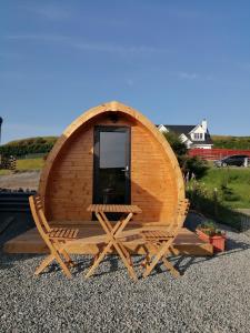 a circular wooden sauna with a chair and a window at Portnalong Pod in Port na Long