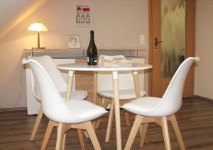 einen Tisch mit weißen Stühlen und eine Flasche Wein in der Unterkunft FEWO Schinkestrasse in Bad Schandau