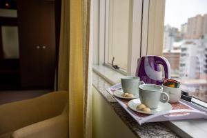 ein Tablett mit zwei Tassen auf einem Fensterbrett in der Unterkunft Villa Vergueiro Hotel in Passo Fundo