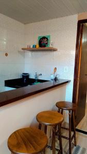 a kitchen with two stools and a counter with a sink at Hospedagem Doce Lar - Casa Girassol in Teresópolis