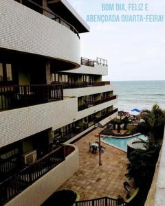a building with a swimming pool next to the ocean at Flat completo a beira mar com vista exuberante no Blue Marlin Apartments in Natal