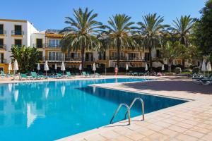 una piscina frente a un hotel con palmeras en Quinta do Morgado - Apartamentos Turisticos Monte Da Eira en Tavira