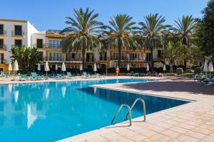 une piscine avec des palmiers en face d'un hôtel dans l'établissement Quinta do Morgado - Apartamentos Turisticos Monte Da Eira, à Tavira