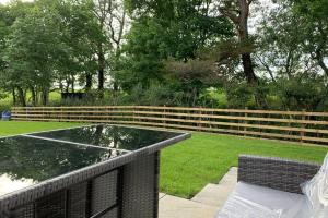 einen Teich im Garten mit einem Zaun in der Unterkunft Nether Newton - Sleeps 10, Hottub, Sauna, Private Garden in Newmilns