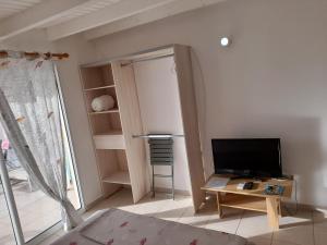 Habitación con cama y mesa con TV. en Le studio de Jeannine, en Capesterre-Belle-Eau