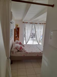 Habitación pequeña con cama y ventana en Le studio de Jeannine, en Capesterre-Belle-Eau