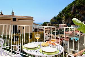 a table with glasses of wine and food on a balcony at Cetara Costa d'Amalfi Residence in Cetara