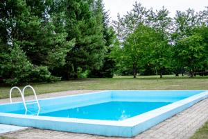 FarynyにあるPENSJONAT FARYNYの木々が茂る公園内の青いスイミングプール