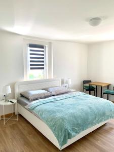 a white bedroom with a large bed with a blue blanket at Pension u Šťastných in Mariánské Lázně