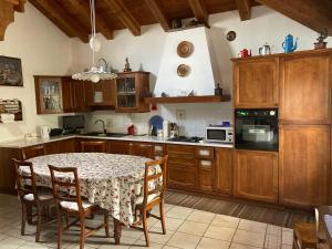 une cuisine avec une table et des chaises et une cuisine avec des placards en bois dans l'établissement La vecchia scuola, à Saint Marcel