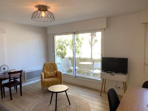 un soggiorno con televisione, tavolo e sedie di Appartement cosy plein centre à 2 pas de la plage a Le Touquet-Paris-Plage