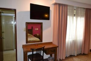 um quarto com uma secretária e uma televisão na parede em Hotel Habana em Cidade do México