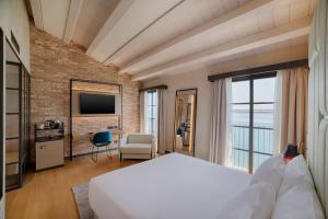 a bedroom with a white bed and a brick wall at NH Collection Murano Villa in Murano