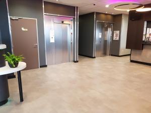 un couloir d'un bureau avec une rangée d'ascenseurs dans l'établissement B&B HOTEL Béthune Bruay-la-Buissière, à Bruay-la-Buissière