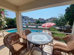 a balcony with a table and chairs and a pool at Orhan Villası in Fethiye
