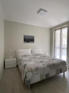 a white bedroom with a bed and a window at La Perla Nera Affittacamere in San Giacomo