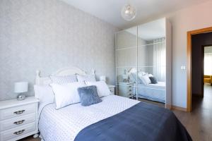 1 dormitorio con cama blanca y espejo en Adeinés Viviendas uso turístico, en A Estrada