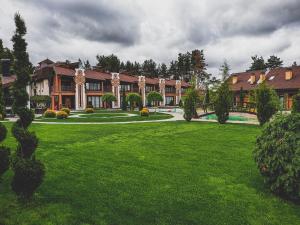 uma casa grande com um relvado verde em frente em Трипільське Сонце em Podgortsy