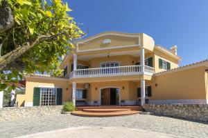 une grande maison jaune avec une terrasse couverte dans l'établissement Monte das Palmeiras, à Loulé