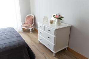 Un dormitorio con una cómoda blanca con un jarrón de flores. en Adeinés Viviendas uso turístico, en A Estrada