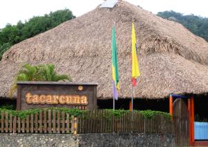 a sign and two flags in front of a thatch hut at Tacarcuna Lodge in Capurganá