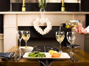 a person pouring wine into a plate of food on a table at White Hart Hotel in St Austell