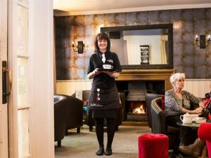 a woman is standing in a room with a mirror at White Hart Hotel in St Austell