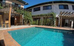 a swimming pool in front of a house at Pousada Naia Suítes in Ubatuba