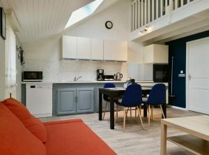 a kitchen and dining room with a table and blue chairs at La Belle symphonie in Vieil-Moutier