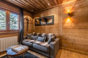 - un canapé en cuir dans une chambre dotée de murs en bois dans l'établissement Flocon des Neiges, à Praz-sur-Arly