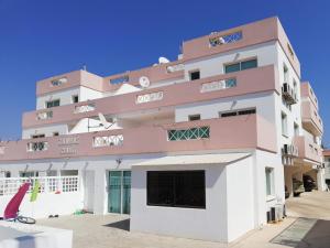 - un bâtiment rose et blanc avec une grande fenêtre dans l'établissement Larnaca Xylophagou 2-bedroom apartment with a shaded terrace, à Xylophaghou