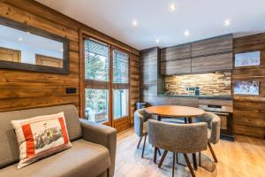 sala de estar con paredes de madera, mesa y sillas en Le Hameau des Neiges, en Praz-sur-Arly