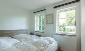 a bedroom with two white beds and two windows at Strandhaus in Ahrenshoop