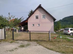 茲拉蒂博爾的住宿－Vikendica Kostic，粉红色的房子,前面有栅栏