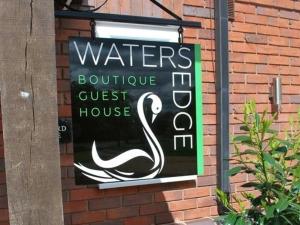 un cartel en un edificio de ladrillo con un cisne en él en The Waters Edge Guest House, en Stratford-upon-Avon