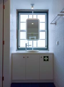 - une télévision assise sur un comptoir dans une salle de bains pourvue d'une fenêtre dans l'établissement Apartamentos Ázera - Laura Ázera, à Praia da Vitória