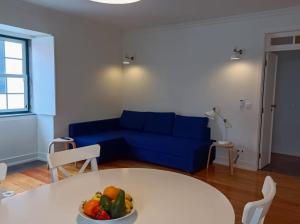 a living room with a blue couch and a table with a bowl of fruit at Apartamentos Ázera - Laura Ázera in Praia da Vitória